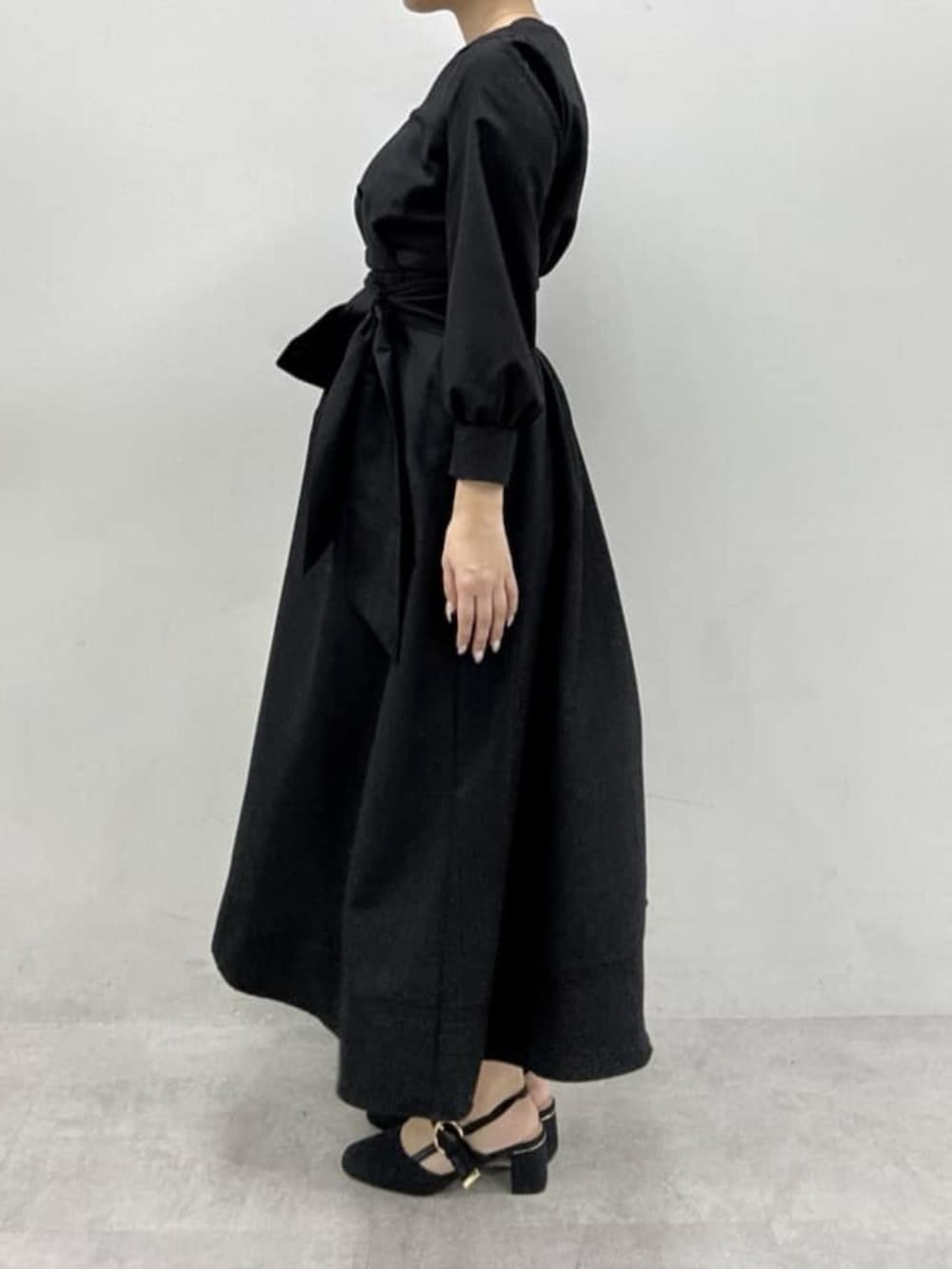 ブラック系のサンダル、ホワイト系のハンドバッグ、ブラック系のワンピースを着用したレディースの冬コーディネートの2枚目の写真