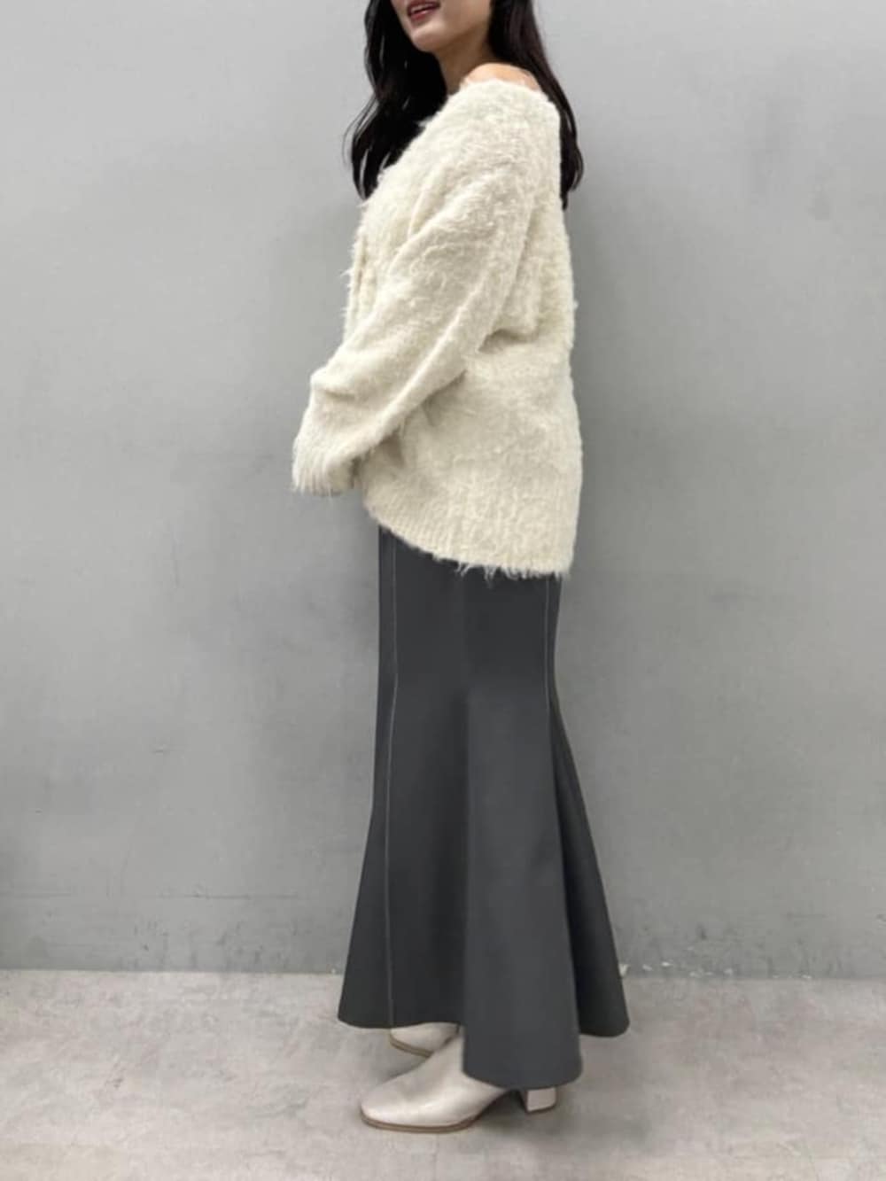 グレー系のスカート、ホワイト系のカーディガン/ボレロを着用したレディースの秋コーディネートの3枚目の写真