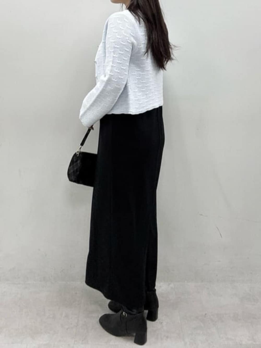 ブラック系のワンピース、ブルー系のカーディガン/ボレロ、ブラック系のハンドバッグを着用したレディースの冬コーディネートの2枚目の写真