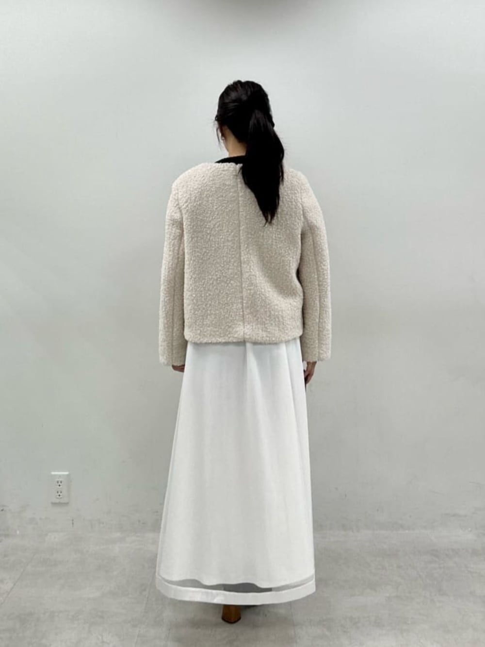 ブラック系のニット/セーター、ホワイト系のスカート、ホワイト系のノーカラージャケットを着用したレディースの秋コーディネートの3枚目の写真