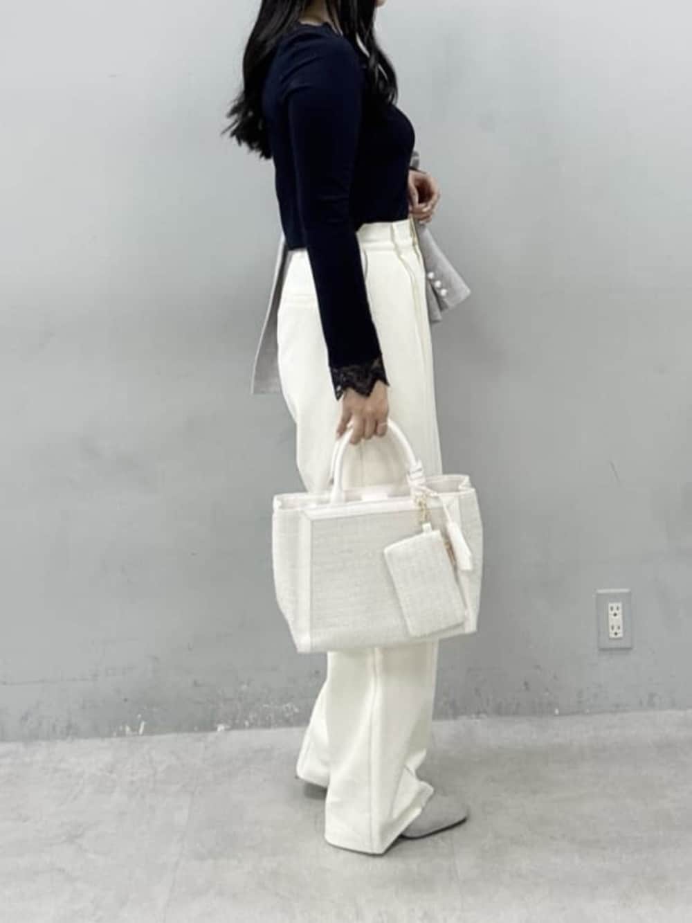 グレー系のテーラードジャケット、ホワイト系のハンドバッグ、ホワイト系のスラックスを着用したレディースの春コーディネートの3枚目の写真