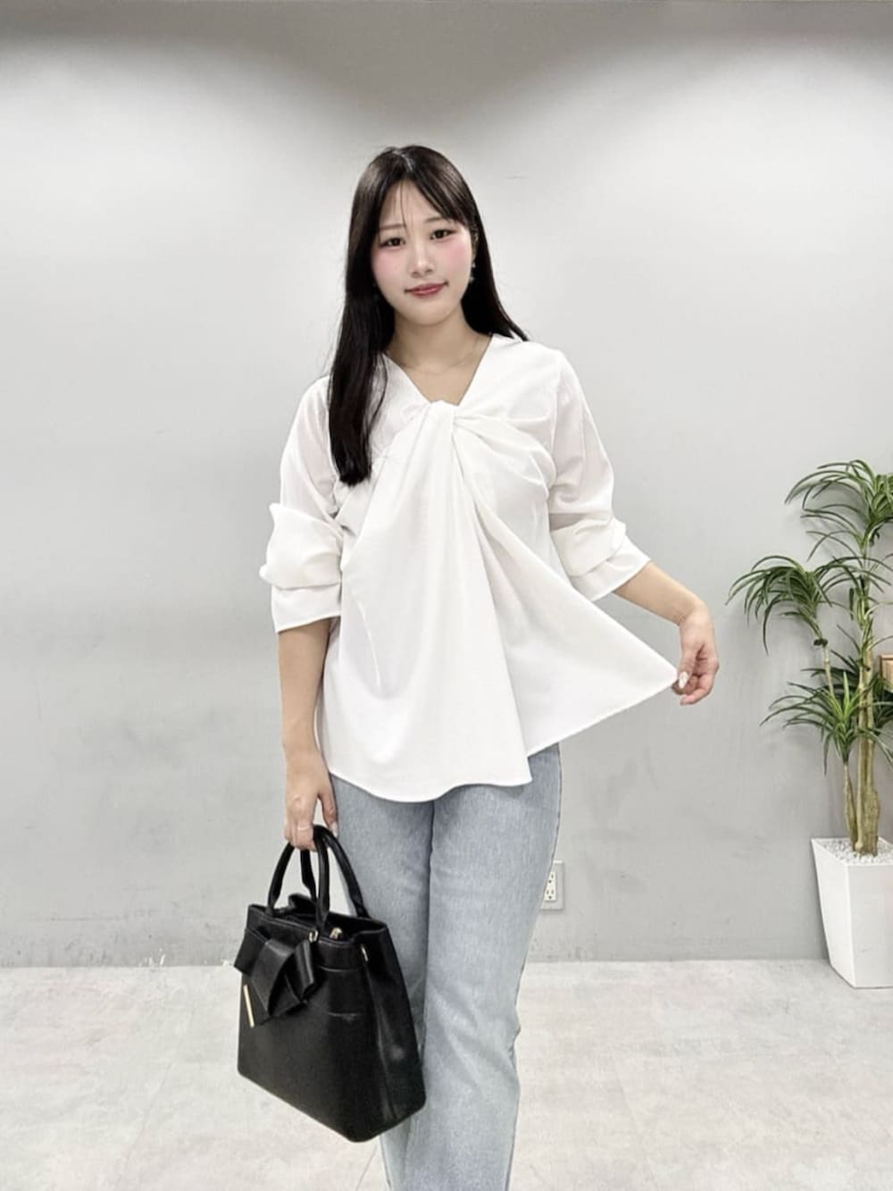 ブルー系のデニムパンツ、ブラック系のショルダーバッグ、ホワイト系のシャツ/ブラウスを着用したレディースの春コーディネートの5枚目の写真