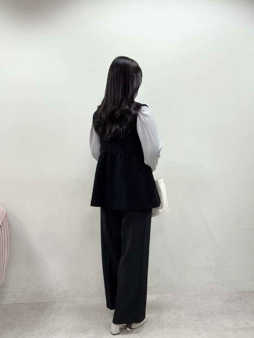 ホワイト系のハンドバッグ、グレー系のサンダル、ブラック系のスラックスを着用したレディースの冬コーディネートの3枚目の写真