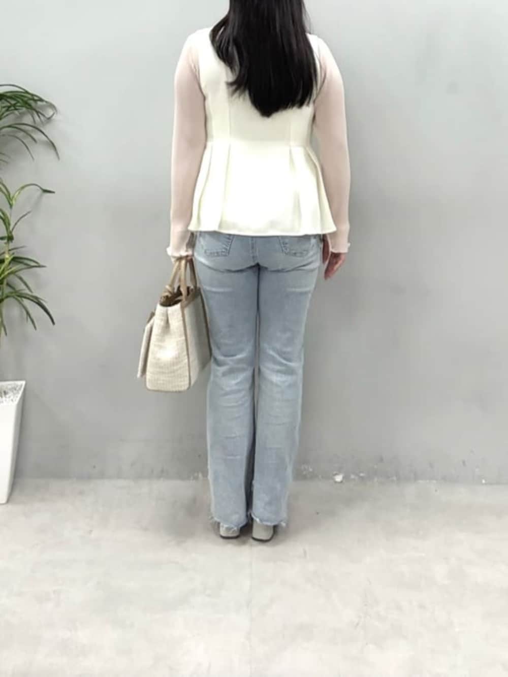 ブルー系のデニムパンツ、ベージュ系のハンドバッグ、ホワイト系のベストを着用したレディースの冬コーディネートの3枚目の写真