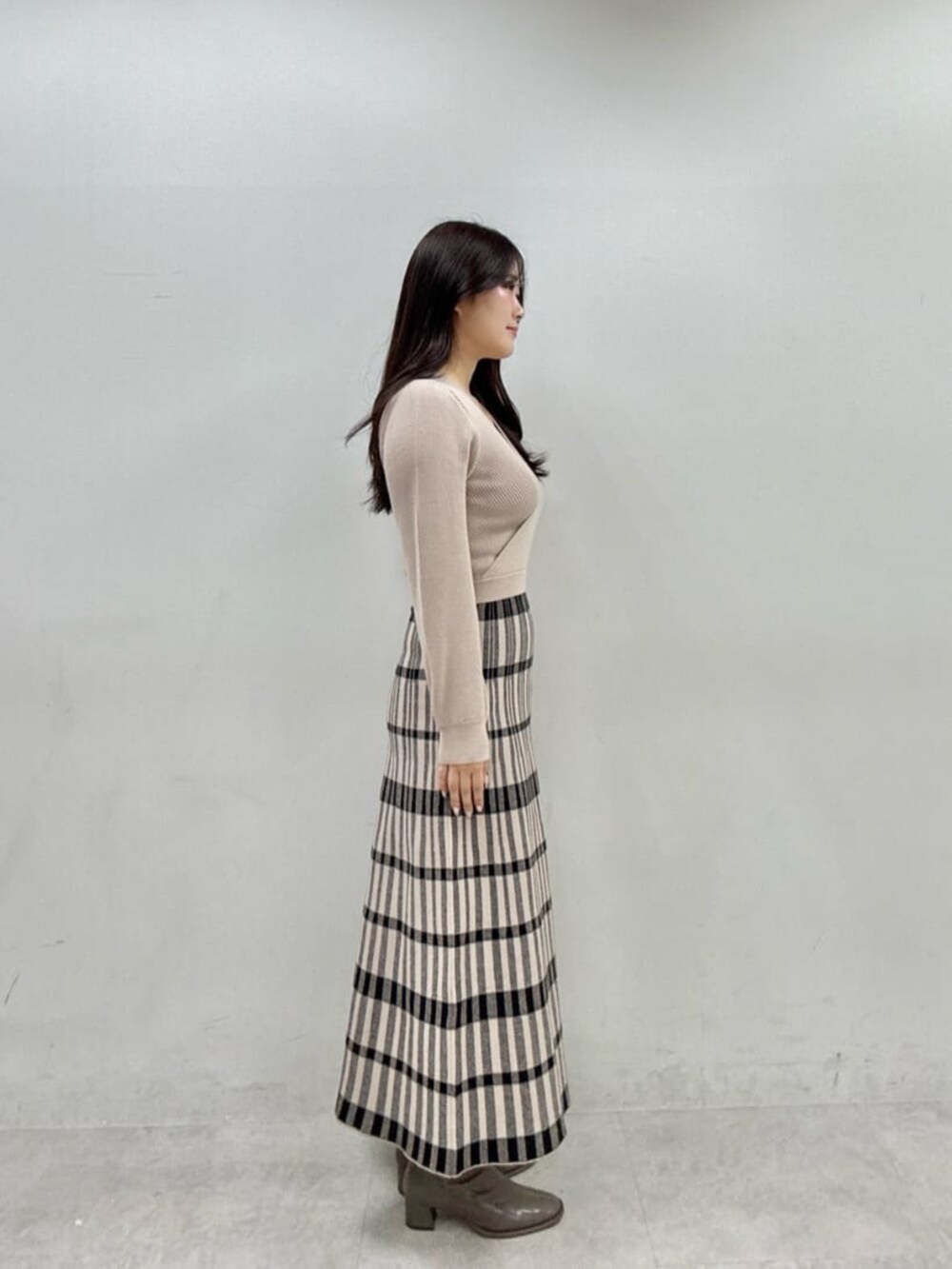 ベージュ系のワンピース、ホワイト系のニット/セーターを着用したレディースの秋コーディネートの5枚目の写真