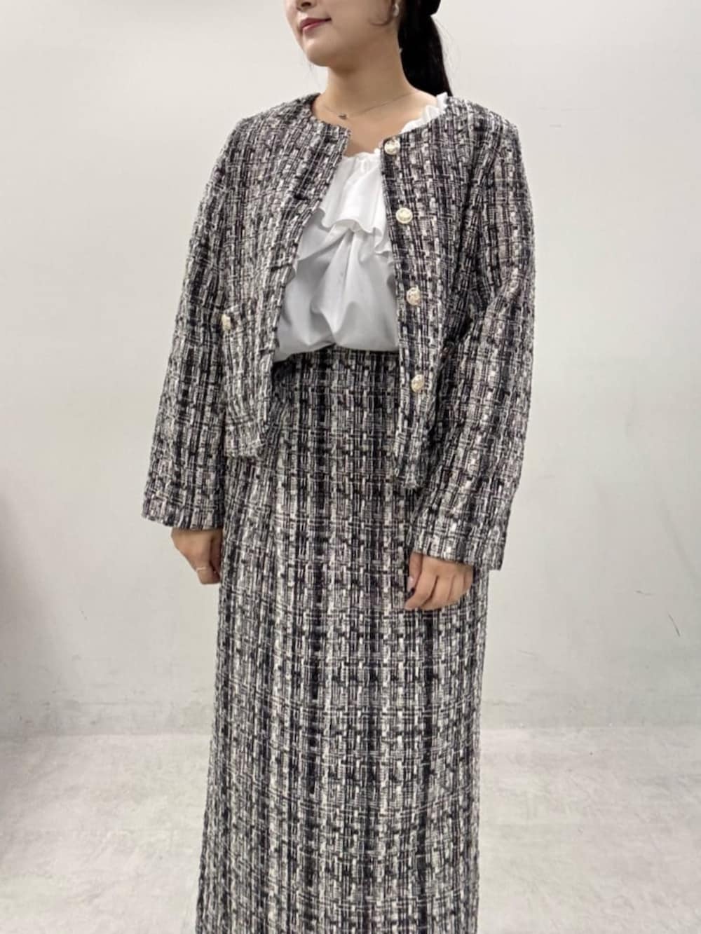 グレー系のスカート、グレー系のノーカラージャケット、ブラック系のブーツを着用したレディースの秋コーディネートの8枚目の写真