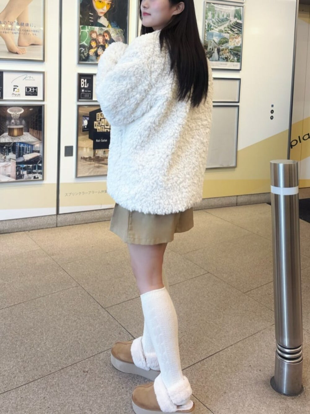 ホワイト系のノーカラーコートを着用したレディースの冬コーディネートの2枚目の写真