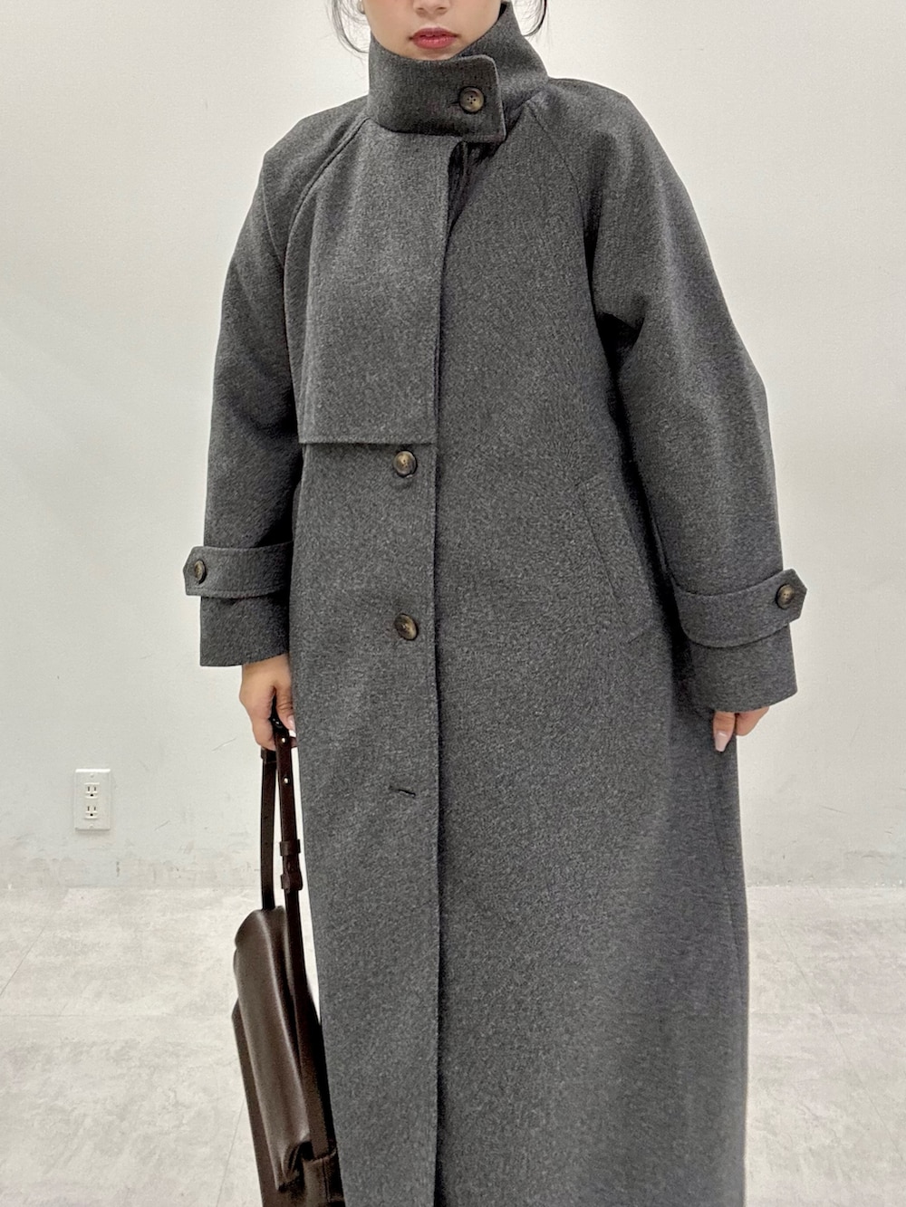 ブラック系のニット/セーター、グレー系のステンカラーコート、ホワイト系のワンピースを着用したレディースの秋コーディネートの7枚目の写真