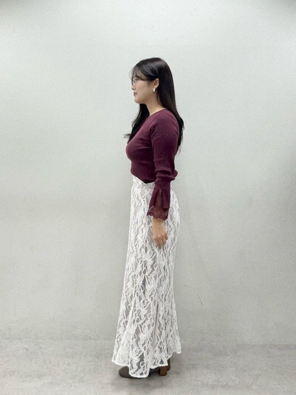 レッド系のニット/セーター、ホワイト系のスカートを着用したレディースの秋コーディネートの2枚目の写真