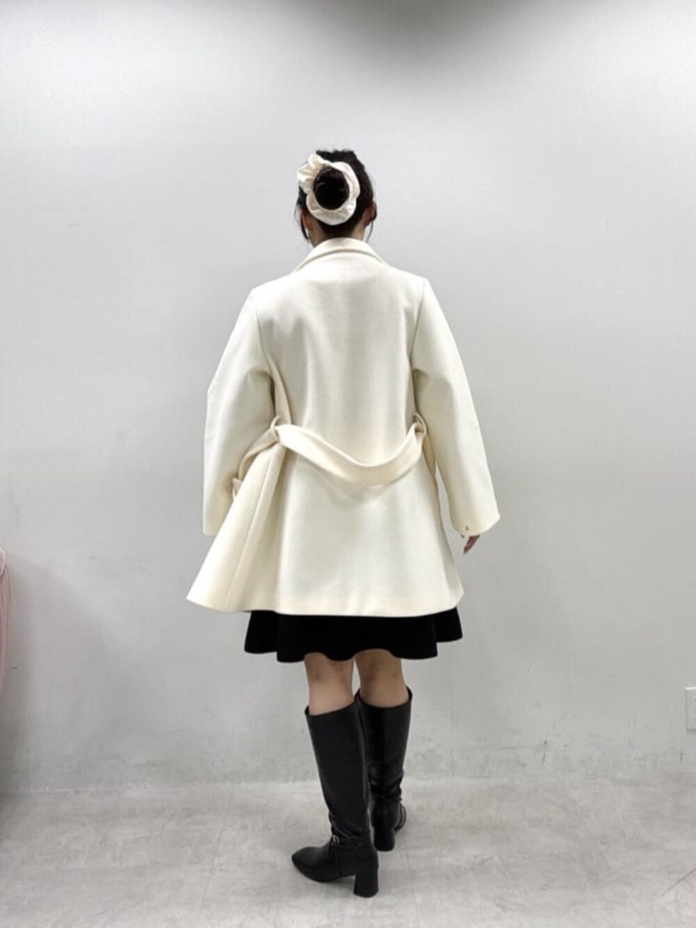 ブラック系のワンピース、ホワイト系のその他アウター、ブラック系のブーツを着用したレディースの秋コーディネートの3枚目の写真