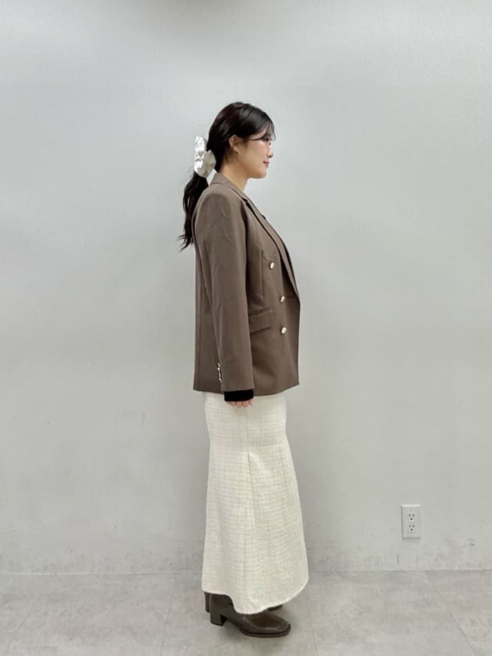 ホワイト系のスカート、ブラウン系のテーラードジャケット、ブラック系のニット/セーターを着用したレディースの秋コーディネートの2枚目の写真