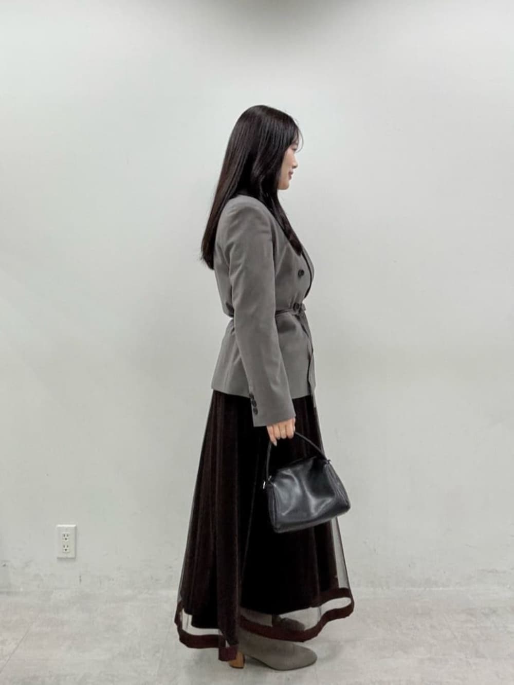 ブラウン系のスカート、グレー系のテーラードジャケットを着用したレディースの秋コーディネートの4枚目の写真