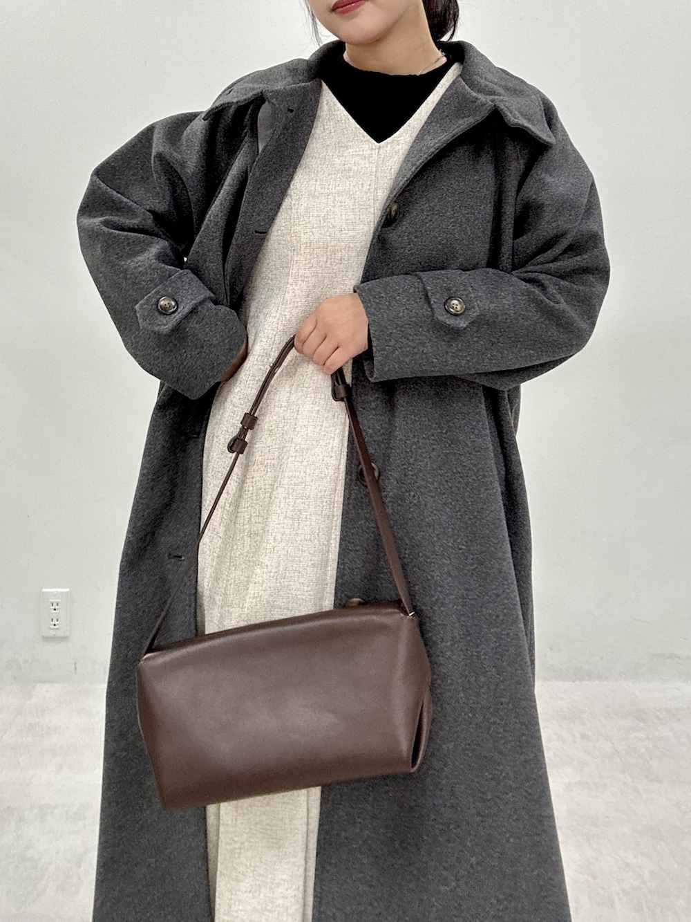 ブラック系のニット/セーター、グレー系のステンカラーコート、ホワイト系のワンピースを着用したレディースの秋コーディネートの5枚目の写真