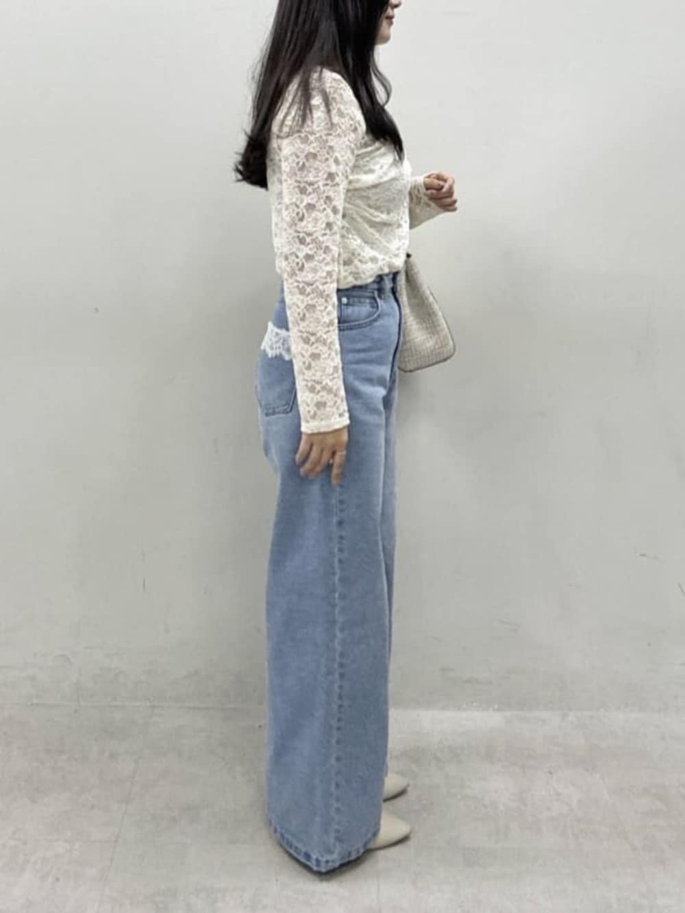 ホワイト系のTシャツ/カットソー、ブルー系のデニムパンツ、ベージュ系のハンドバッグを着用したレディースの冬コーディネートの2枚目の写真