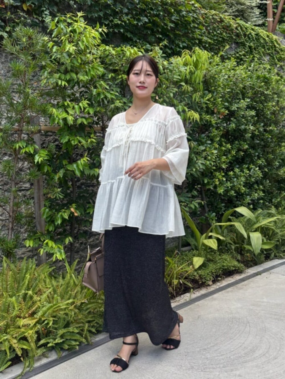 ブラック系のスカート、ホワイト系のシャツ/ブラウスを着用したレディースの夏コーディネートの3枚目の写真