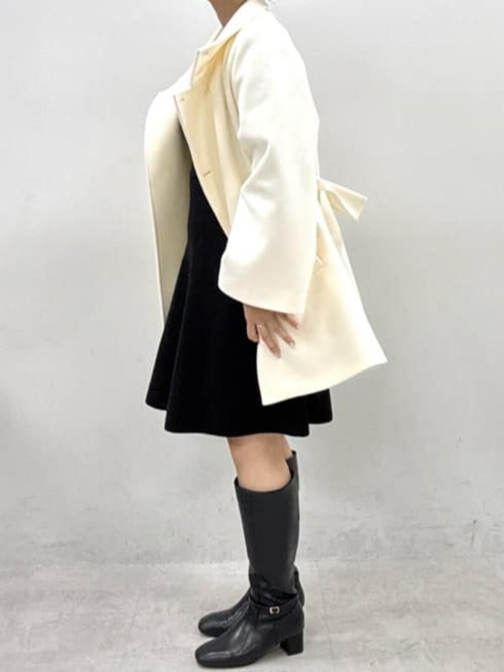 ブラック系のワンピース、ホワイト系のその他アウター、ブラック系のブーツを着用したレディースの秋コーディネートの2枚目の写真