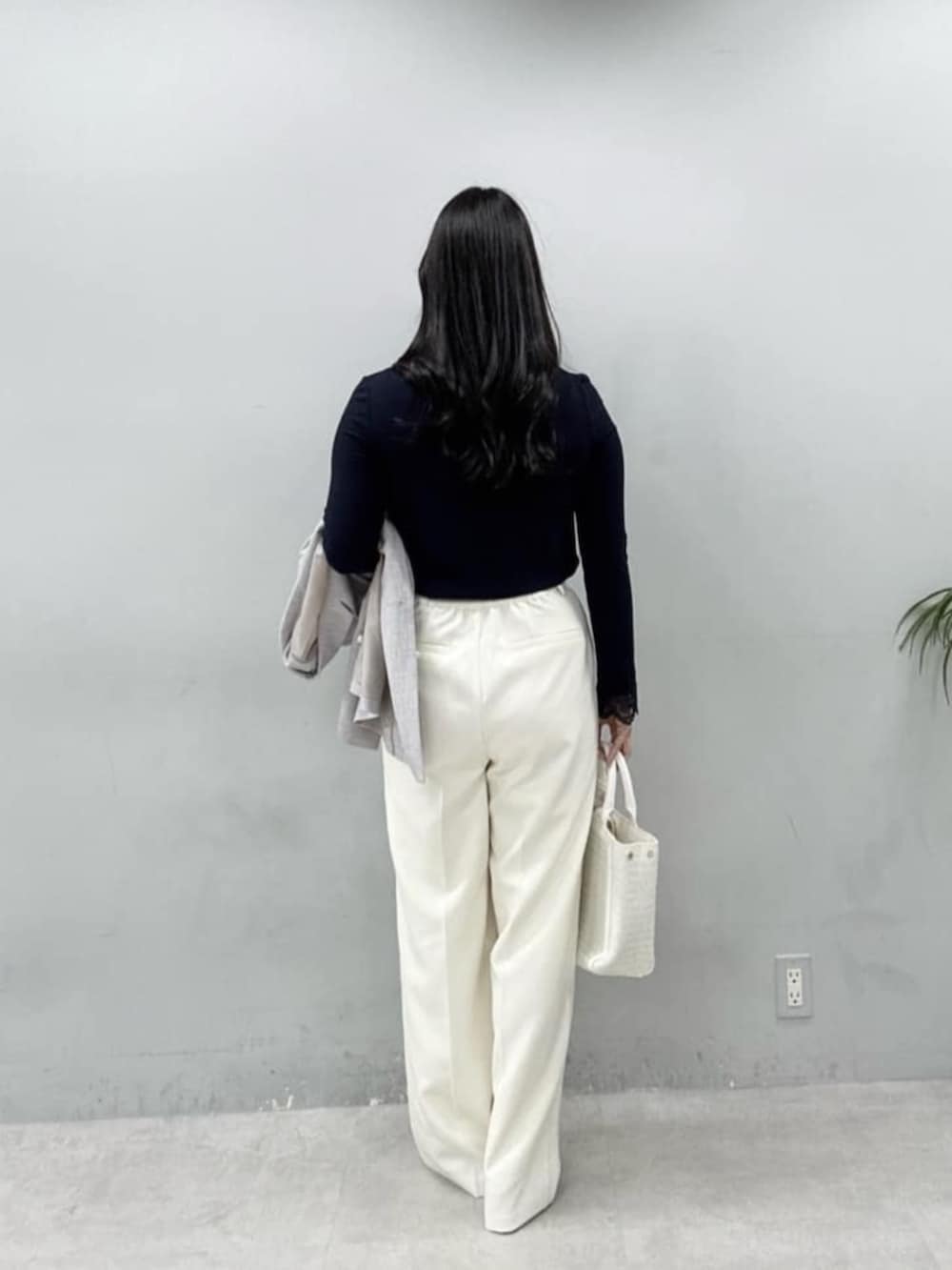 グレー系のテーラードジャケット、ホワイト系のハンドバッグ、ホワイト系のスラックスを着用したレディースの春コーディネートの4枚目の写真