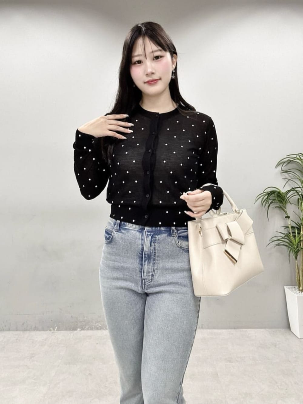 ブルー系のデニムパンツ、ホワイト系のショルダーバッグ、ブラック系のカーディガン/ボレロを着用したレディースの春コーディネートの4枚目の写真