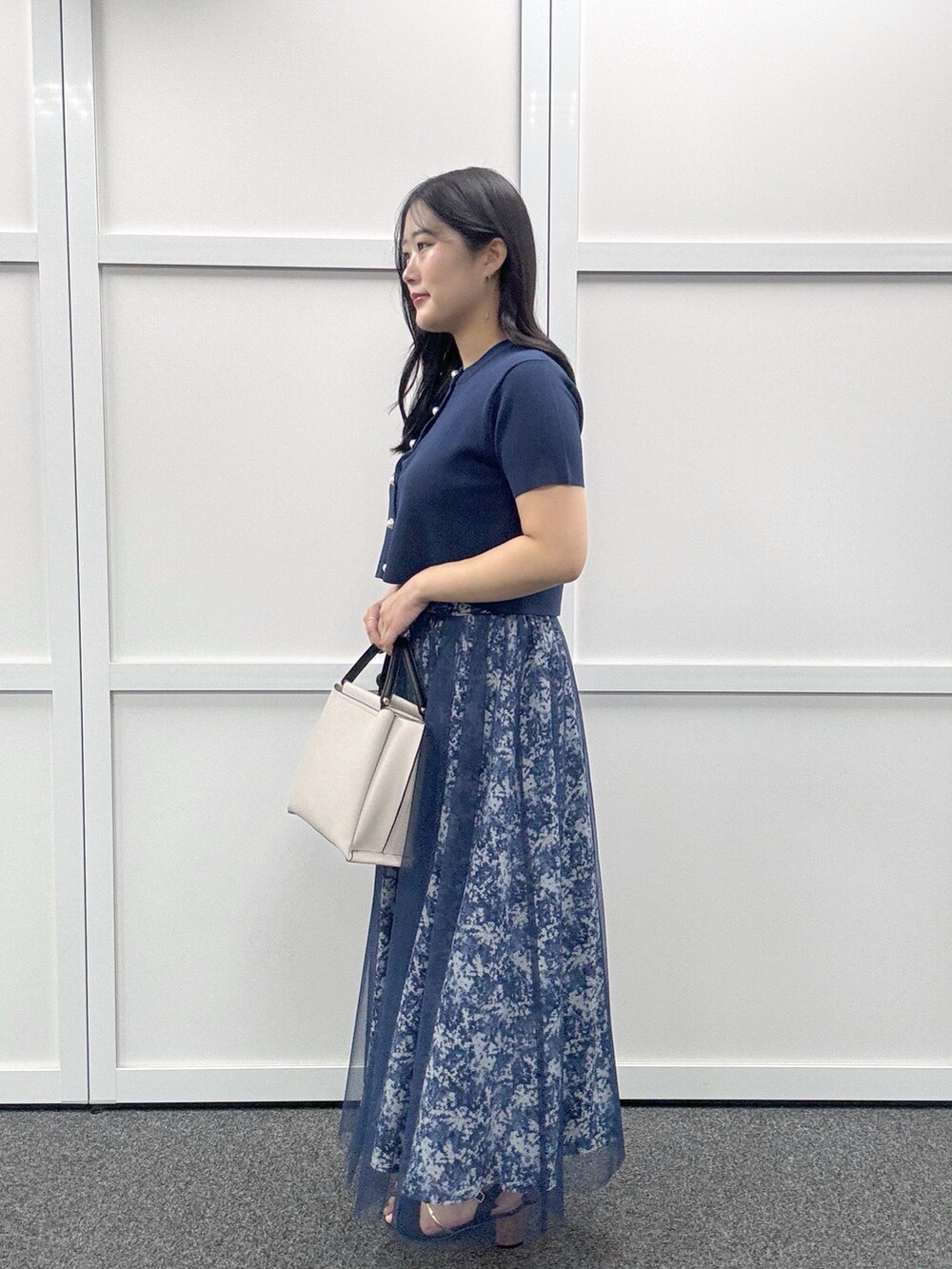 グレー系のショルダーバッグ、ブルー系のカーディガン/ボレロ、その他のスカートを着用したレディースの春コーディネートの2枚目の写真