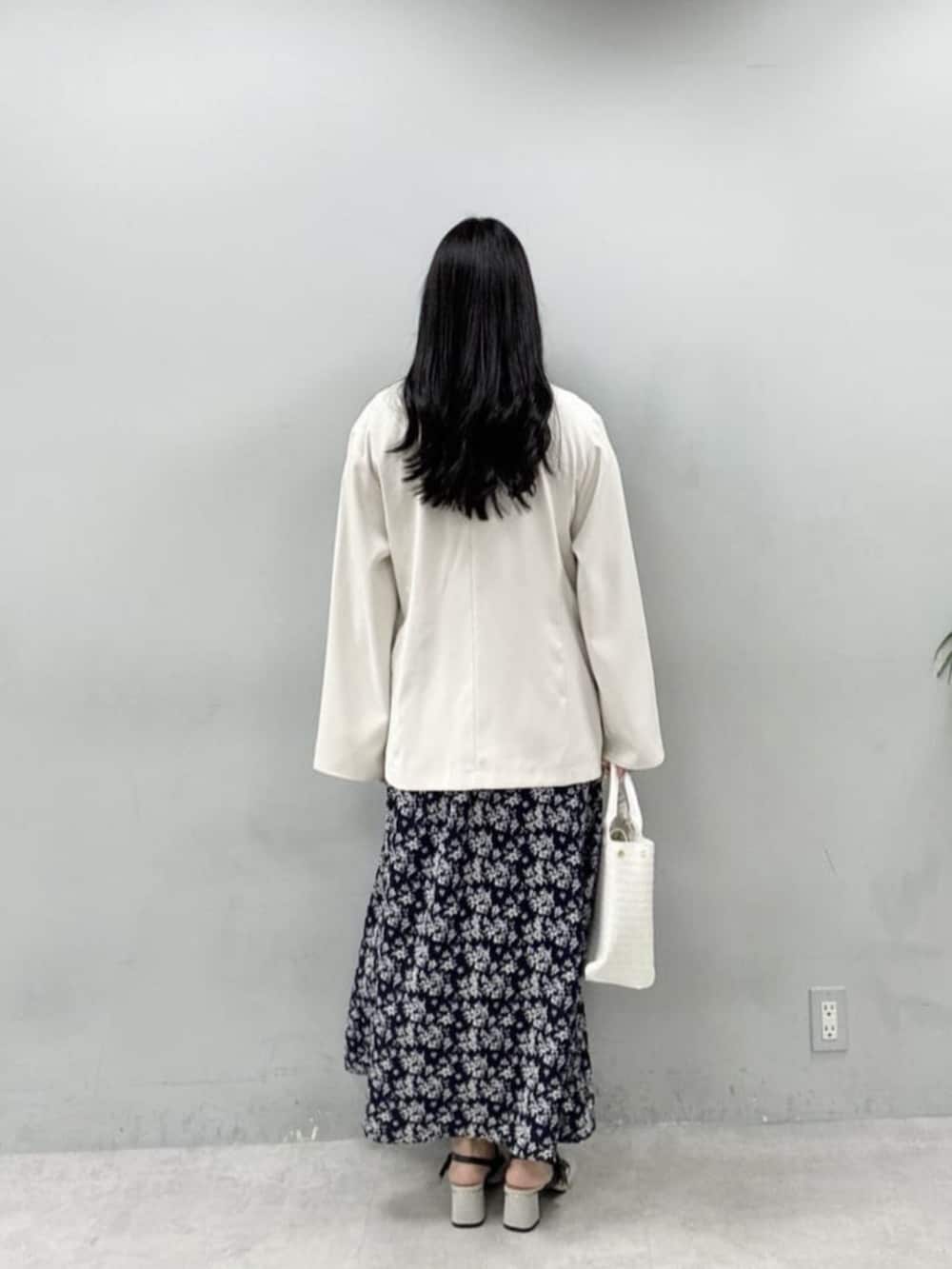 ホワイト系のテーラードジャケット、ホワイト系のハンドバッグ、グレー系のサンダルを着用したレディースの冬コーディネートの3枚目の写真