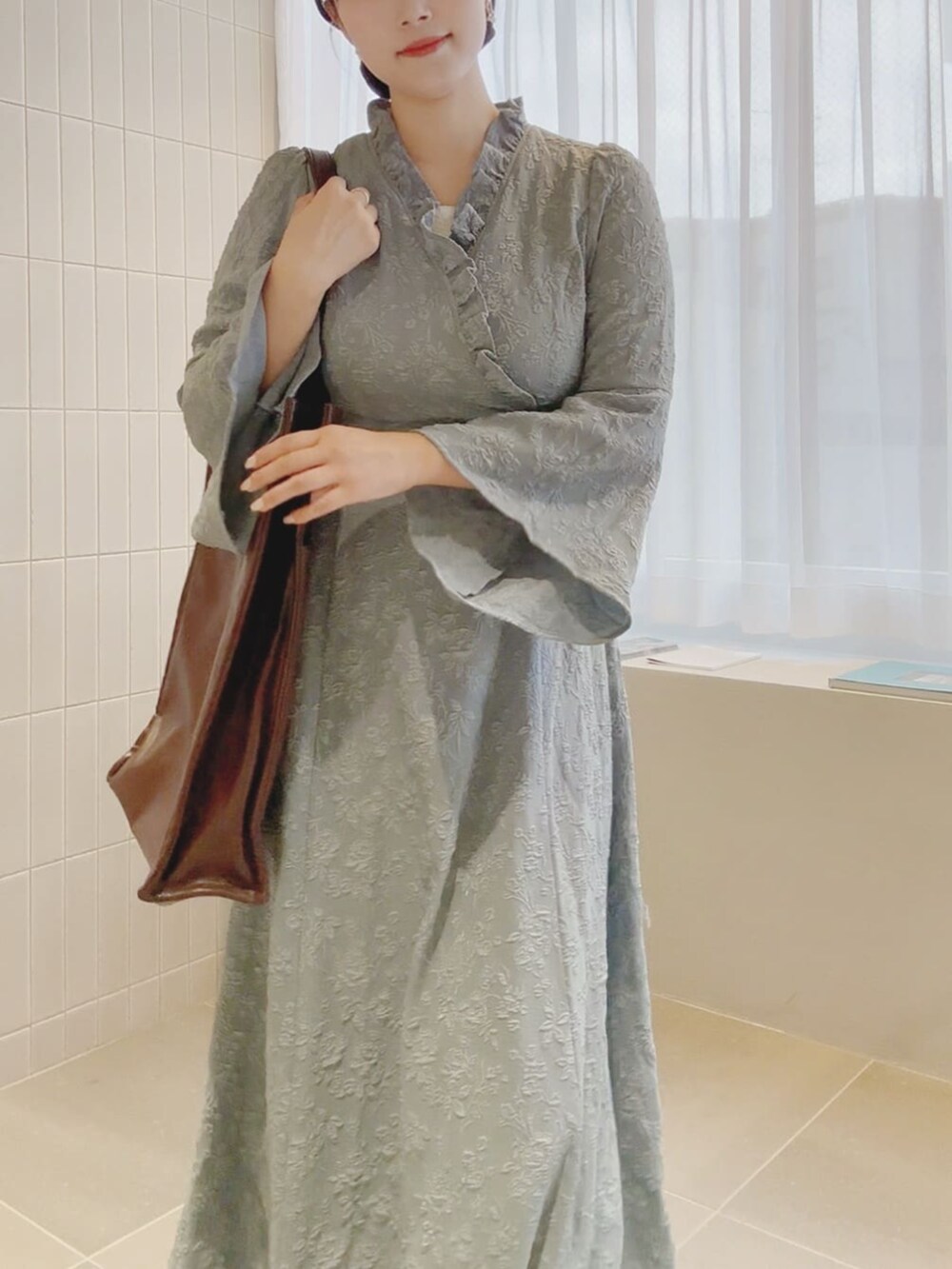 ブラウン系のトートバッグ、ブルー系のワンピースを着用したレディースの秋コーディネートの4枚目の写真