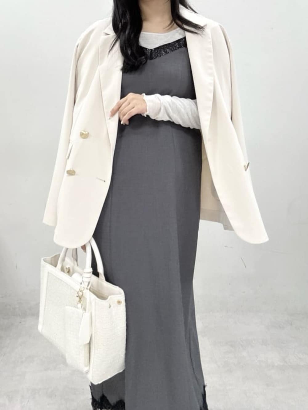 ホワイト系のテーラードジャケット、ホワイト系のハンドバッグ、グレー系のサンダルを着用したレディースの冬コーディネートの3枚目の写真