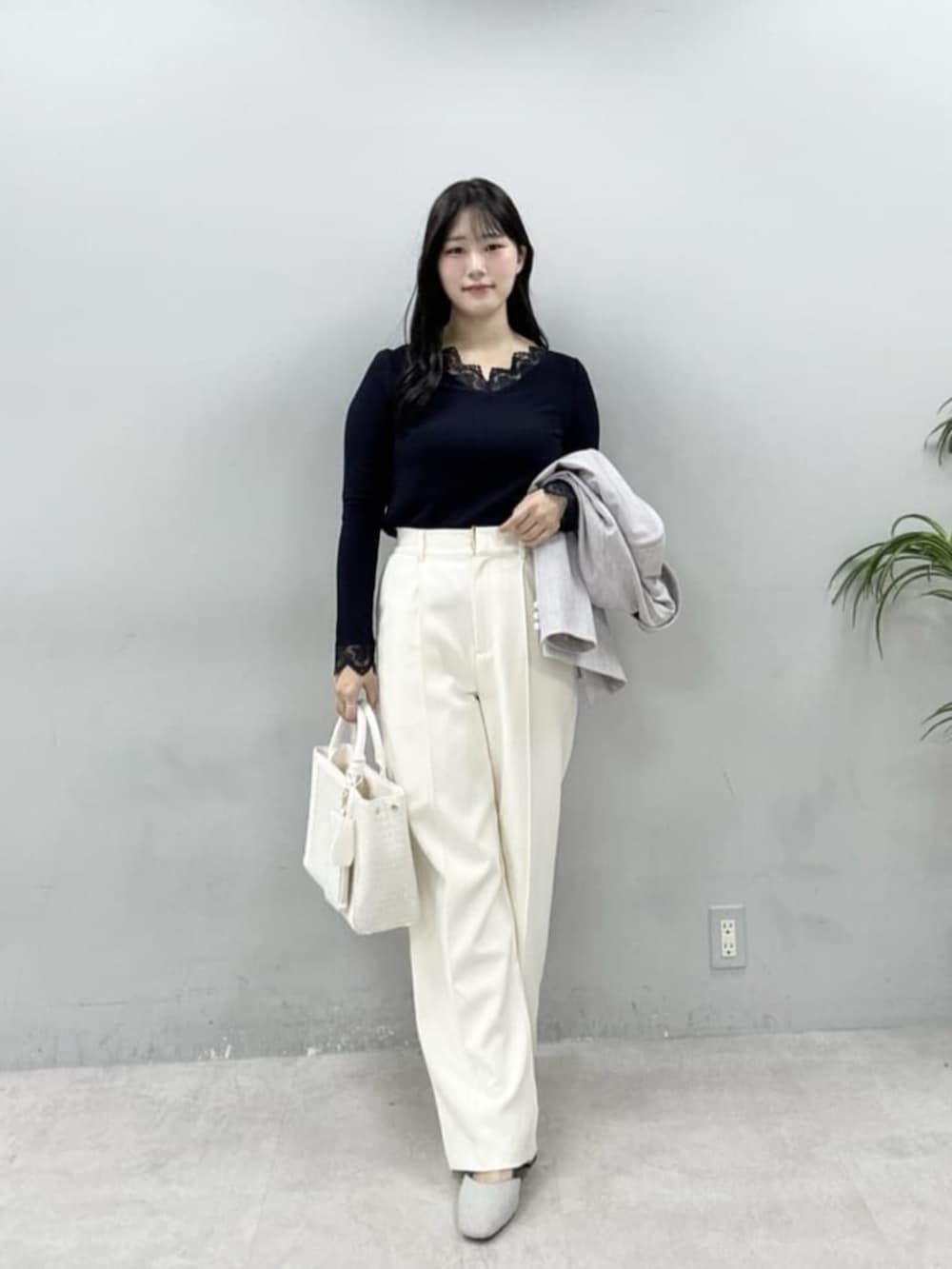 グレー系のテーラードジャケット、ホワイト系のハンドバッグ、ホワイト系のスラックスを着用したレディースの春コーディネートの2枚目の写真