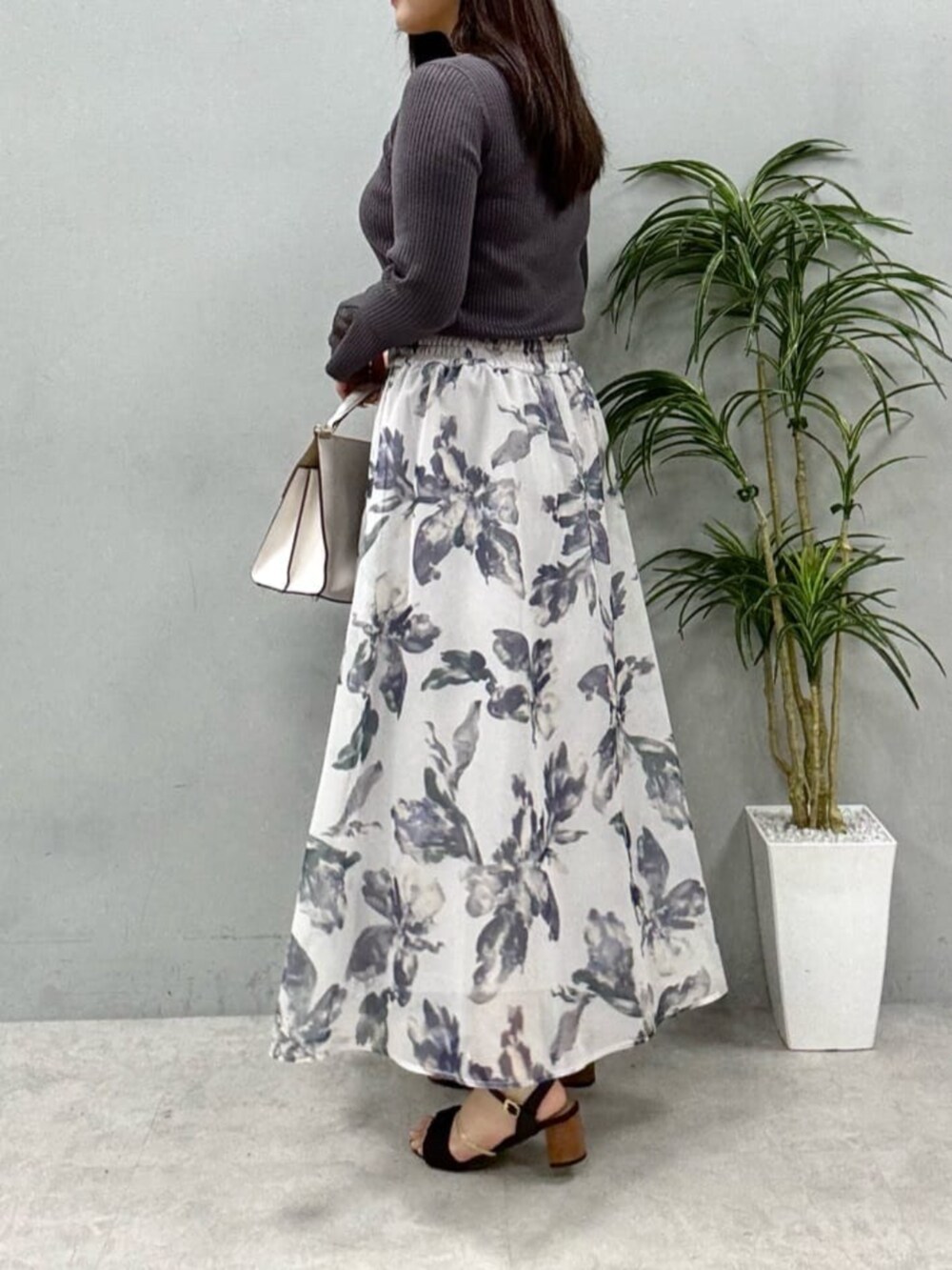 グレー系のニット/セーター、ホワイト系のスカートを着用したレディースの夏コーディネートの2枚目の写真