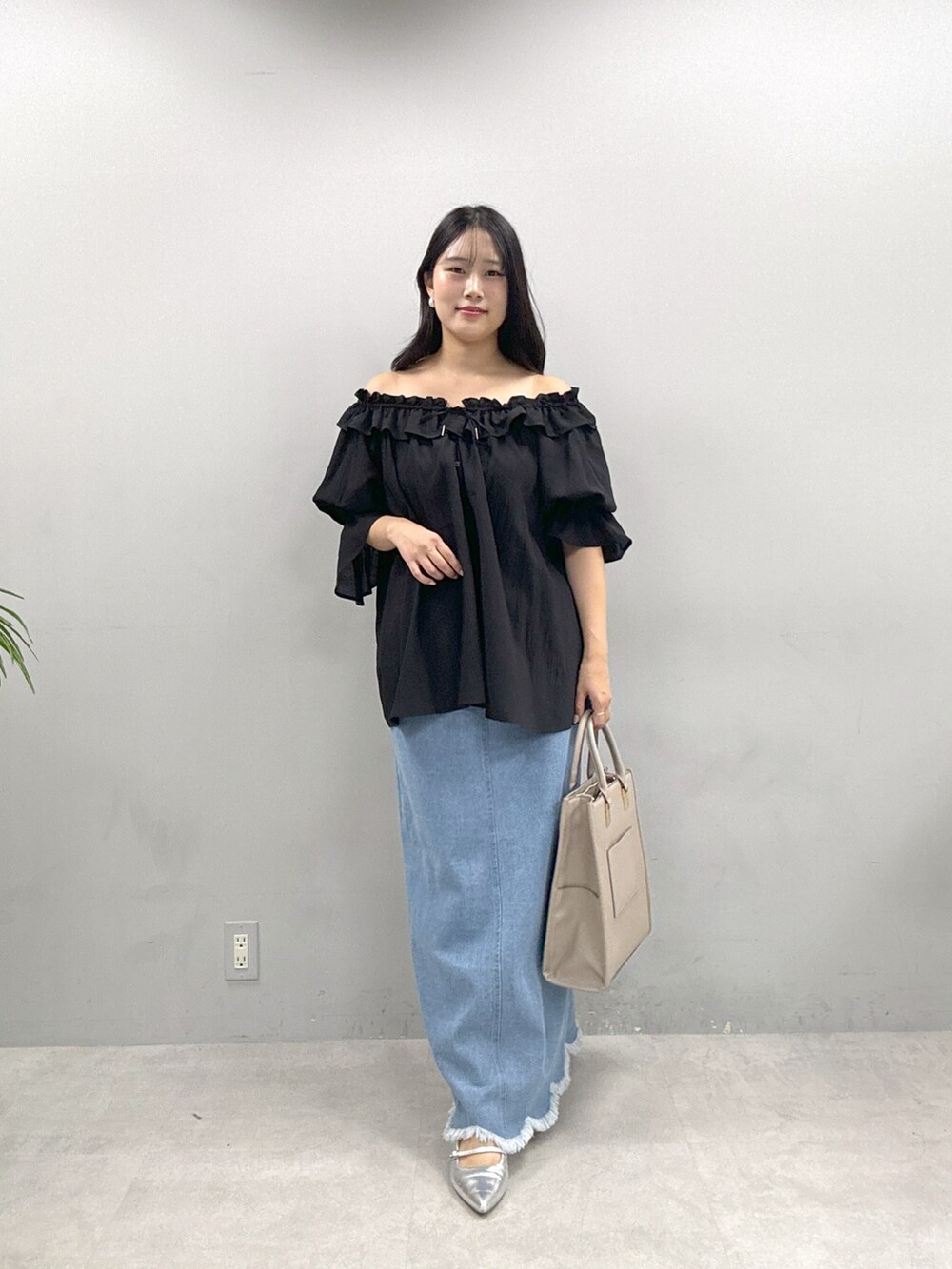 ベージュ系のショルダーバッグ、ブラック系のシャツ/ブラウス、ブルー系のスカートを着用したレディースの春コーディネートの2枚目の写真