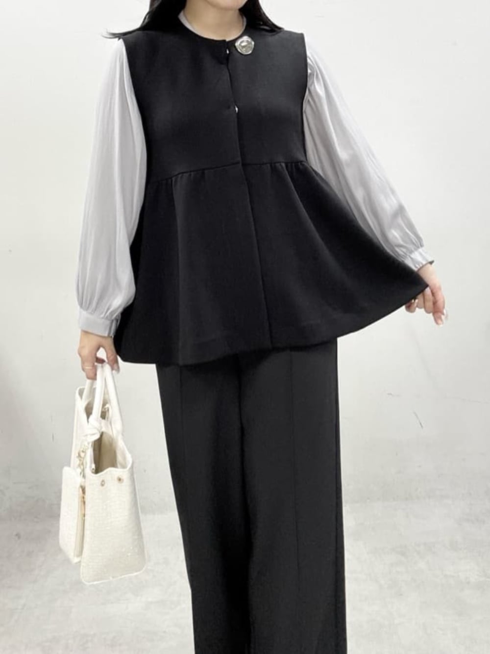 ホワイト系のハンドバッグ、グレー系のサンダル、ブラック系のスラックスを着用したレディースの冬コーディネートの4枚目の写真