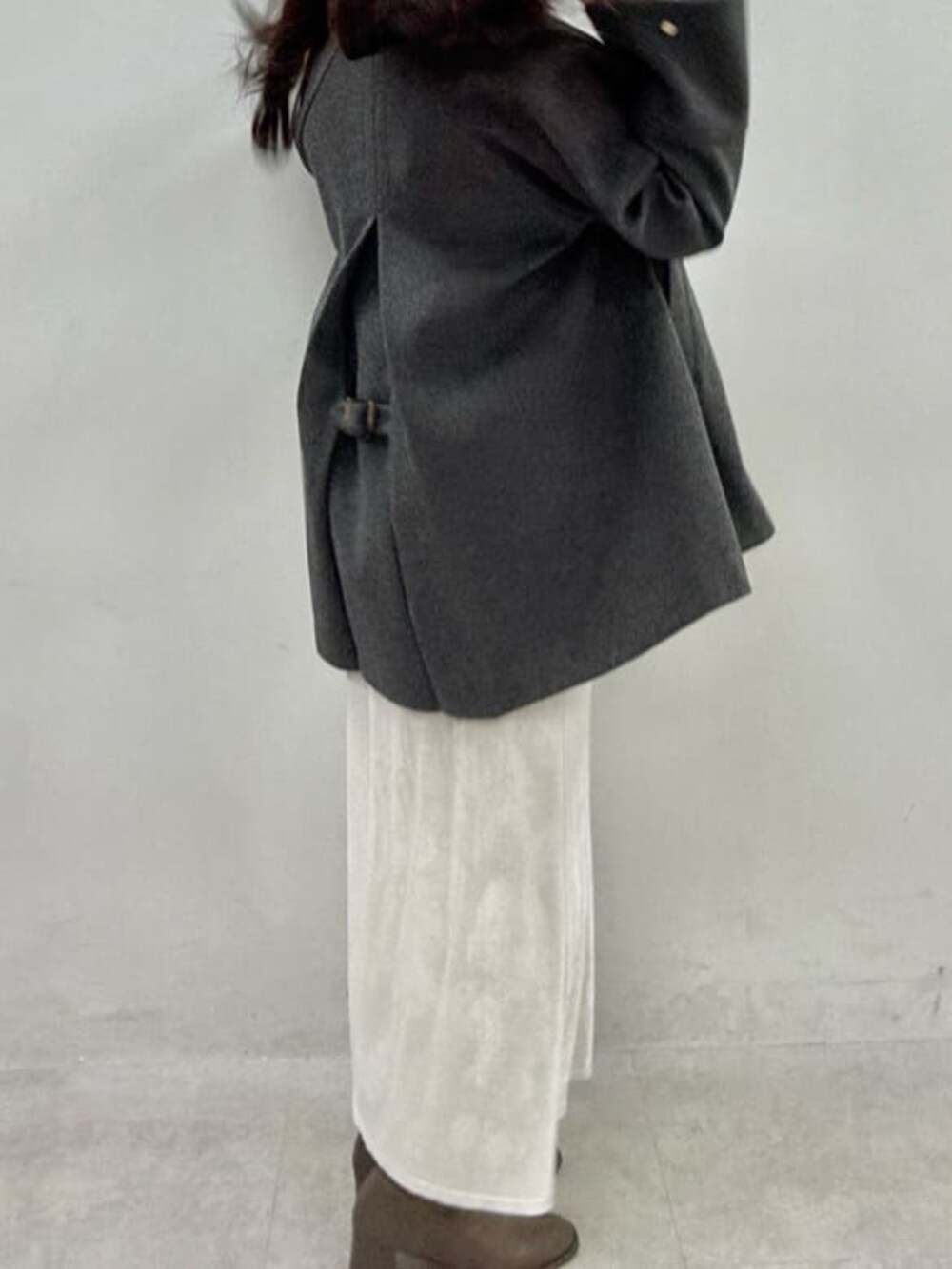 グレー系のノーカラーコート、ホワイト系のスカート、グレー系のニット/セーターを着用したレディースの秋コーディネートの3枚目の写真