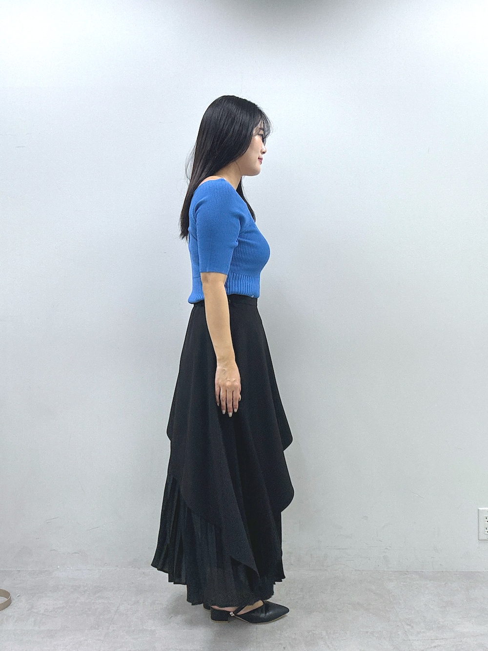 ブラック系のスカート、ブルー系のニット/セーターを着用したレディースの春コーディネートの2枚目の写真