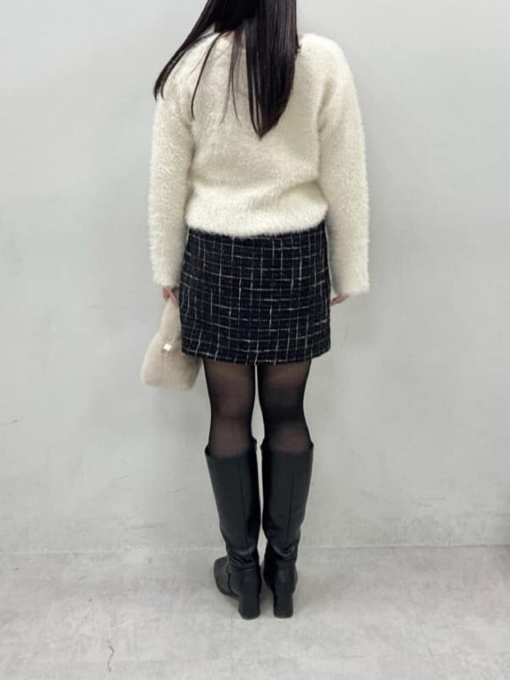 ブラック系のスカート、ホワイト系のニット/セーターを着用したレディースの冬コーディネートの3枚目の写真