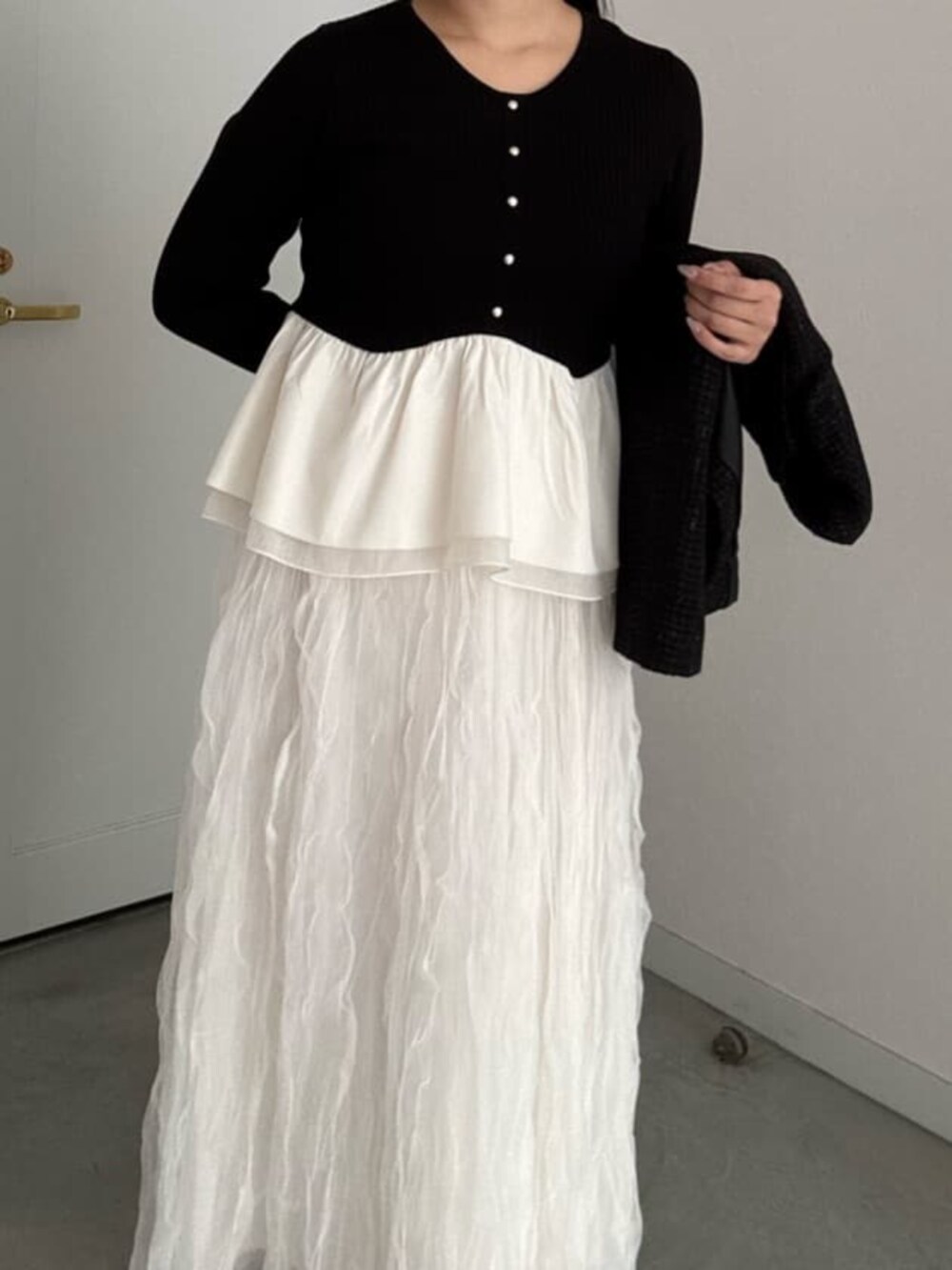 ブラック系のニット/セーター、ホワイト系のスカートを着用したレディースの冬コーディネートの5枚目の写真