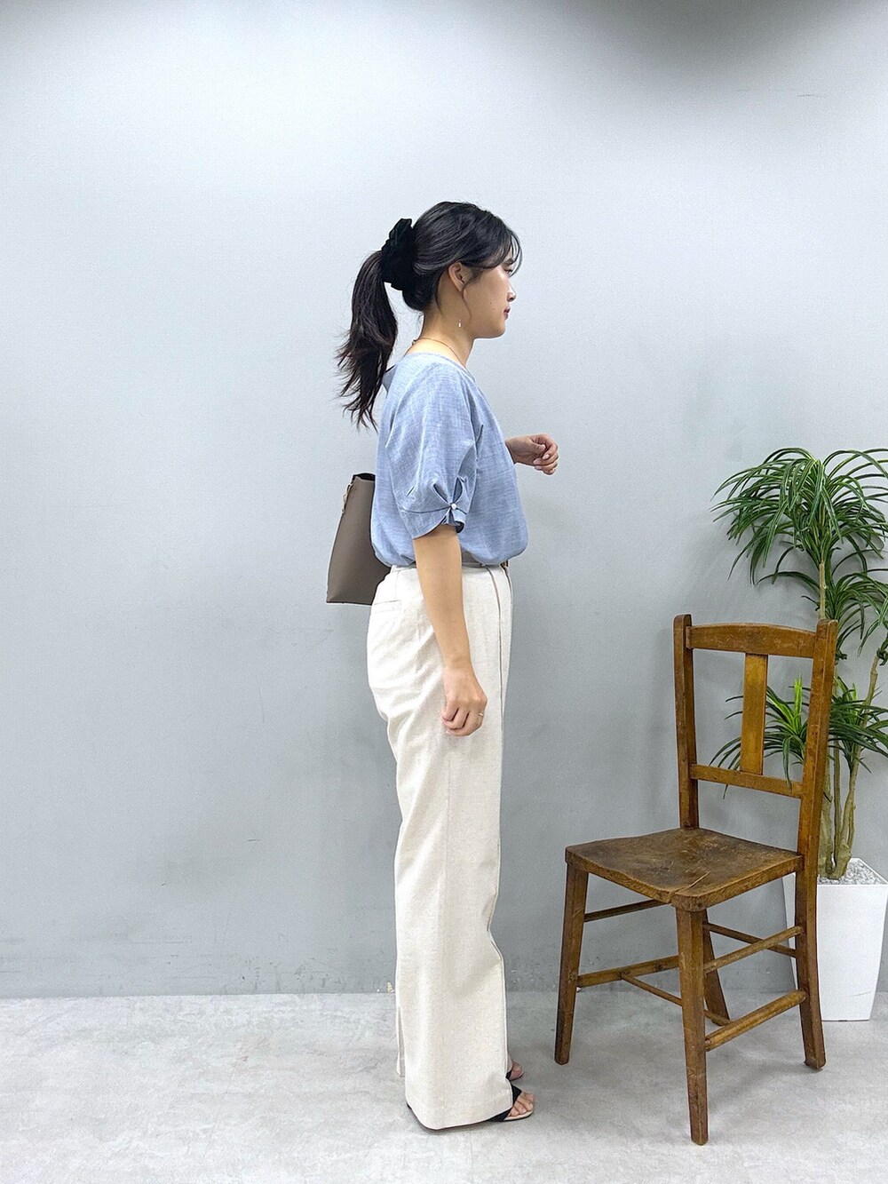 ブラウン系のショルダーバッグ、ベージュ系のその他パンツ、ブルー系のシャツ/ブラウスを着用したレディースの春コーディネートの2枚目の写真