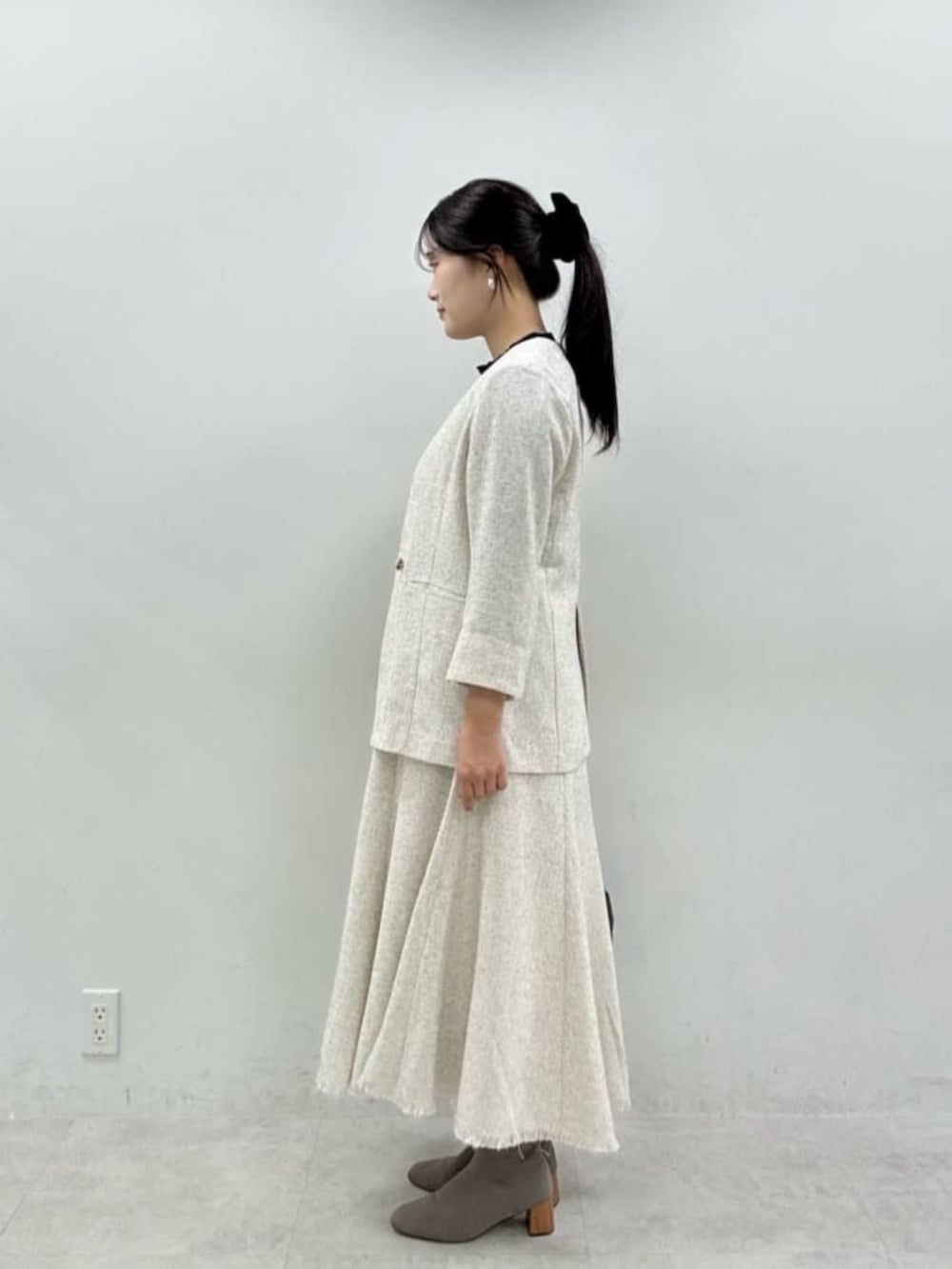 ブラック系のニット/セーター、ホワイト系のワンピース、ホワイト系のノーカラージャケットを着用したレディースの秋コーディネートの2枚目の写真