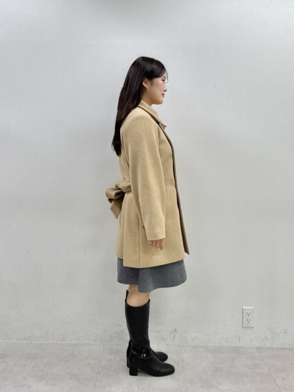 ブラック系のブーツ、ベージュ系のその他アウター、グレー系のワンピースを着用したレディースの秋コーディネートの2枚目の写真