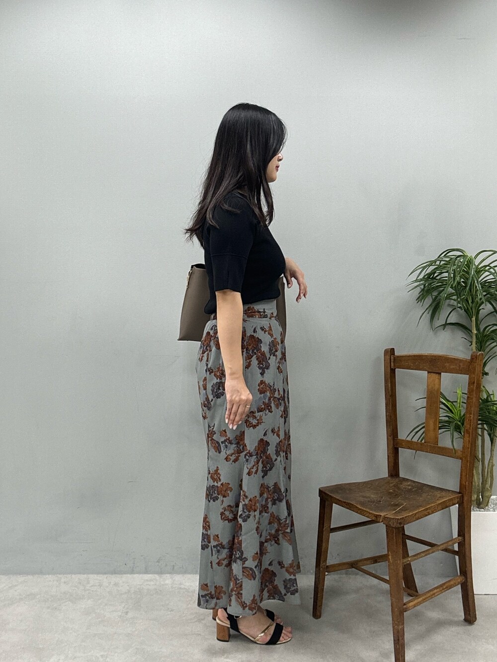 ブラウン系のショルダーバッグ、グレー系のスカート、ブラック系のニット/セーターを着用したレディースの春コーディネートの2枚目の写真