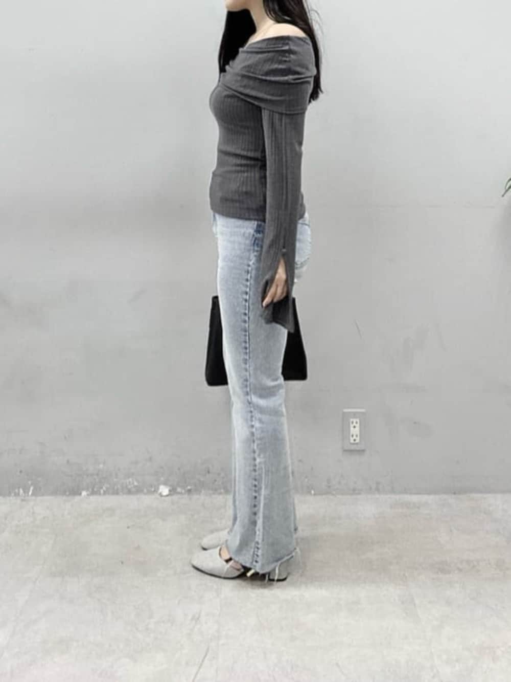 ブルー系のデニムパンツ、ブラック系のショルダーバッグ、グレー系のニット/セーターを着用したレディースの春コーディネートの2枚目の写真