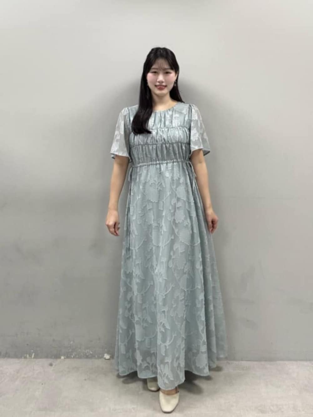 グリーン系のワンピースを着用したレディースの春コーディネートの2枚目の写真