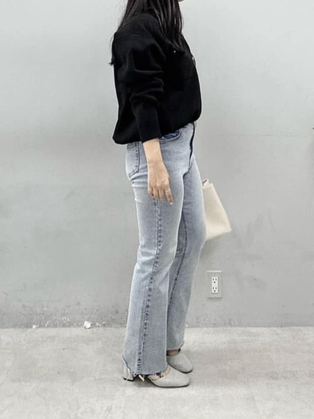 ブルー系のデニムパンツ、ホワイト系のニット/セーター、ブラック系のブルゾンを着用したレディースの春コーディネートの2枚目の写真