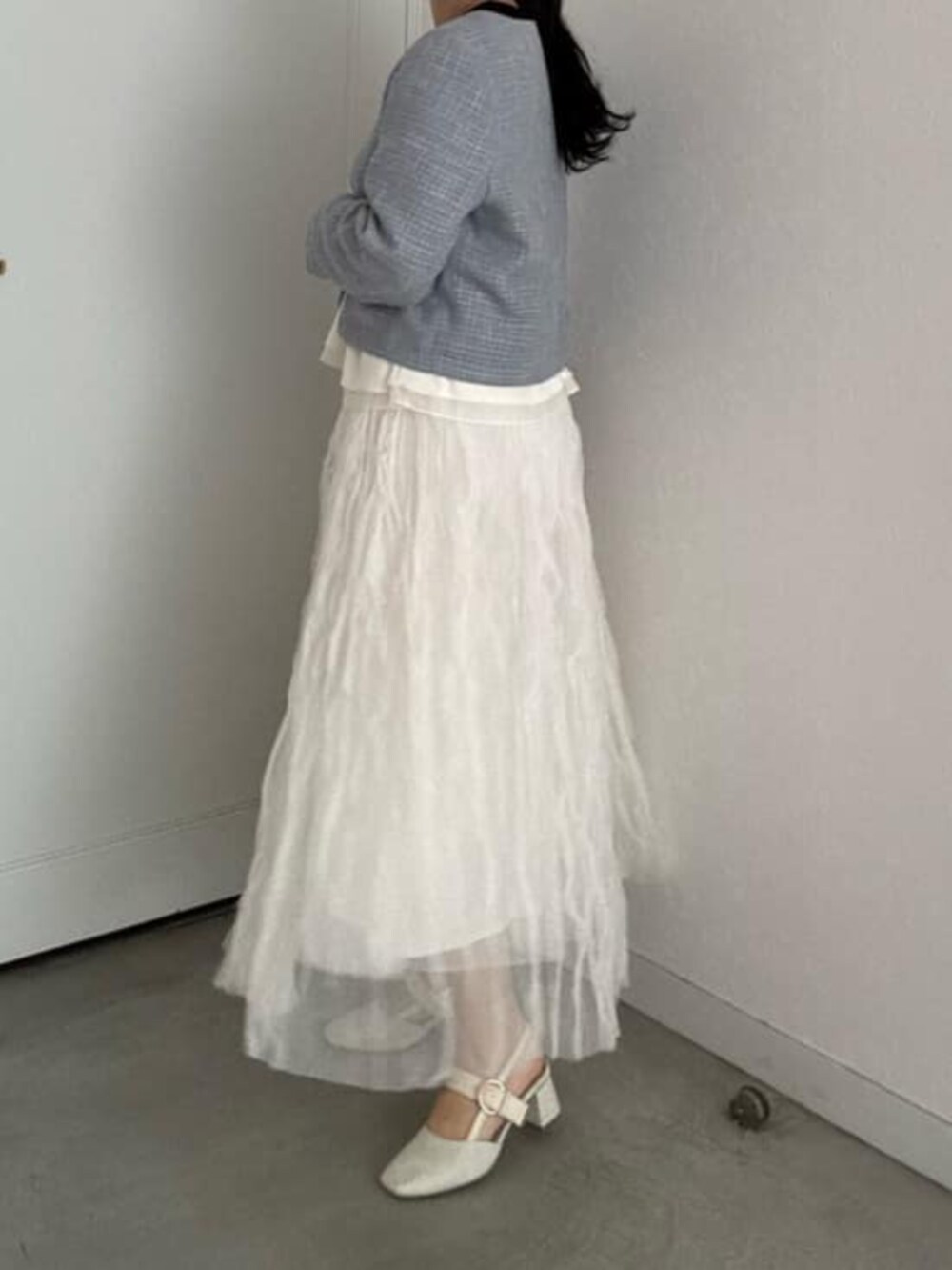 ブラック系のニット/セーター、ホワイト系のサンダル、ホワイト系のスカートを着用したレディースの冬コーディネートの2枚目の写真