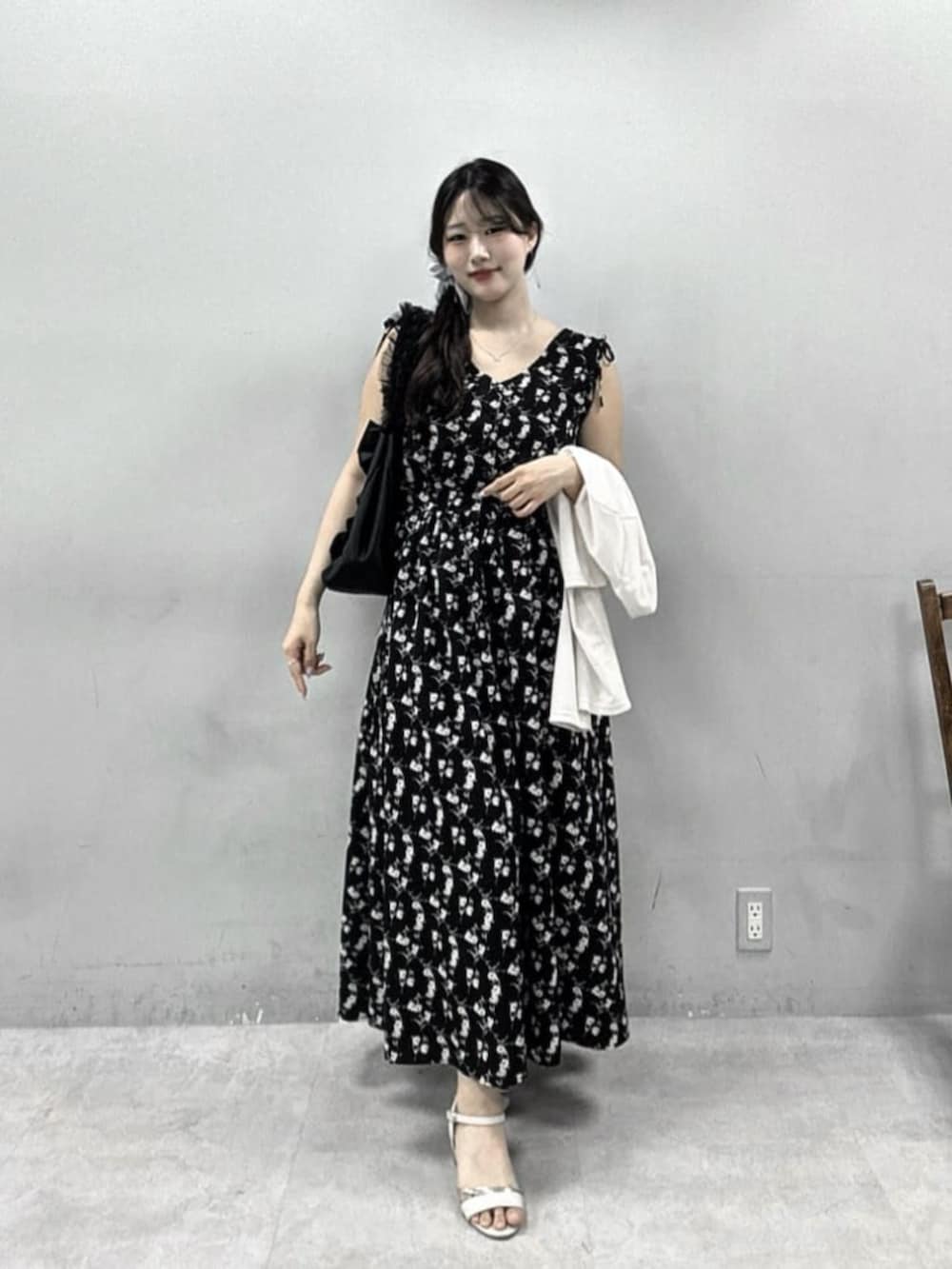 ブラック系のワンピース、ホワイト系のカーディガン/ボレロ、ブラック系のトートバッグを着用したレディースの夏コーディネートの2枚目の写真