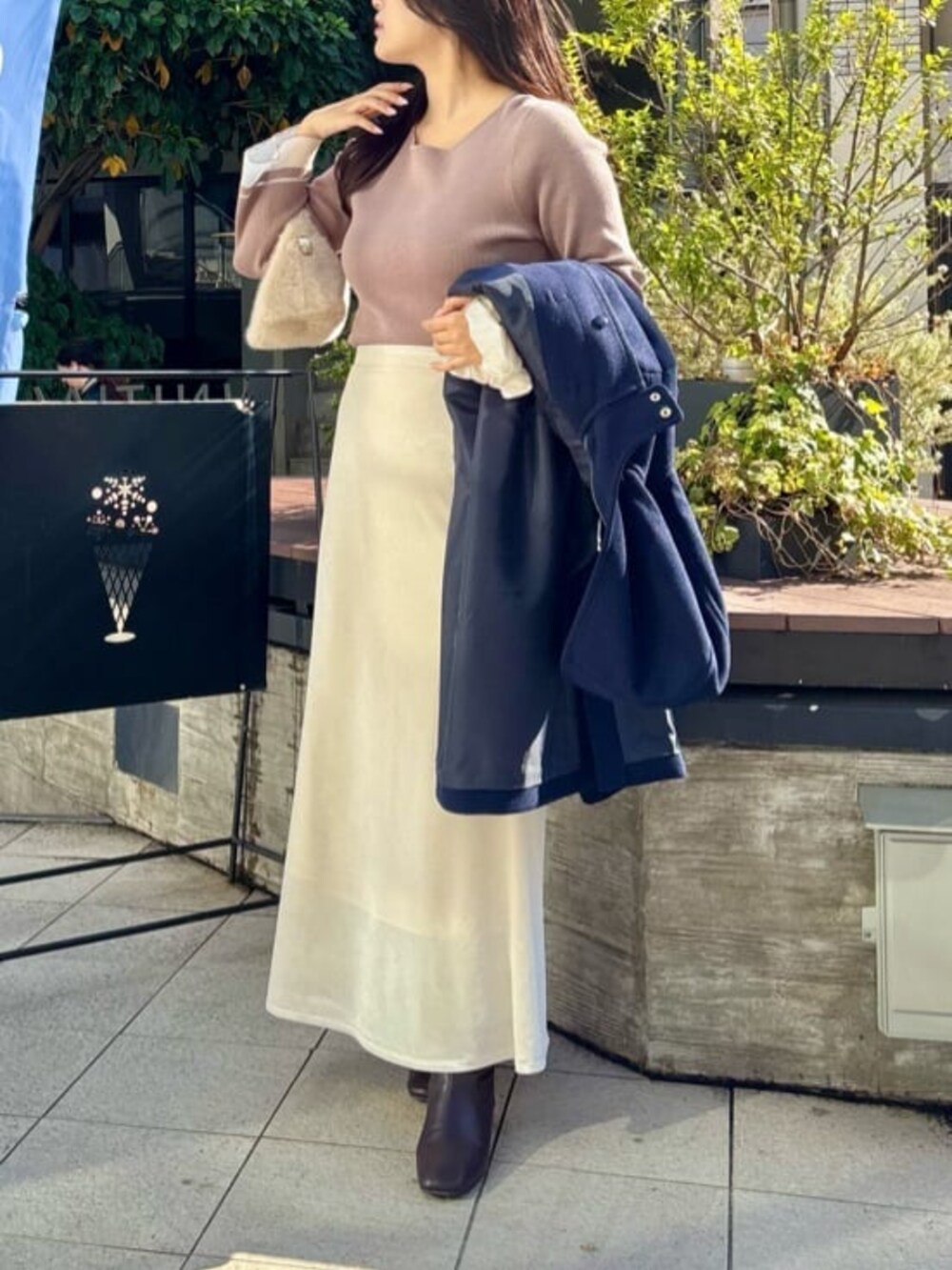 ホワイト系のスカート、ベージュ系のニット/セーターを着用したレディースの冬コーディネートの2枚目の写真