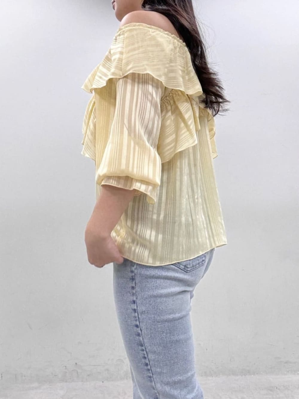 イエロー系のシャツ/ブラウス、ブルー系のデニムパンツを着用したレディースの冬コーディネートの6枚目の写真