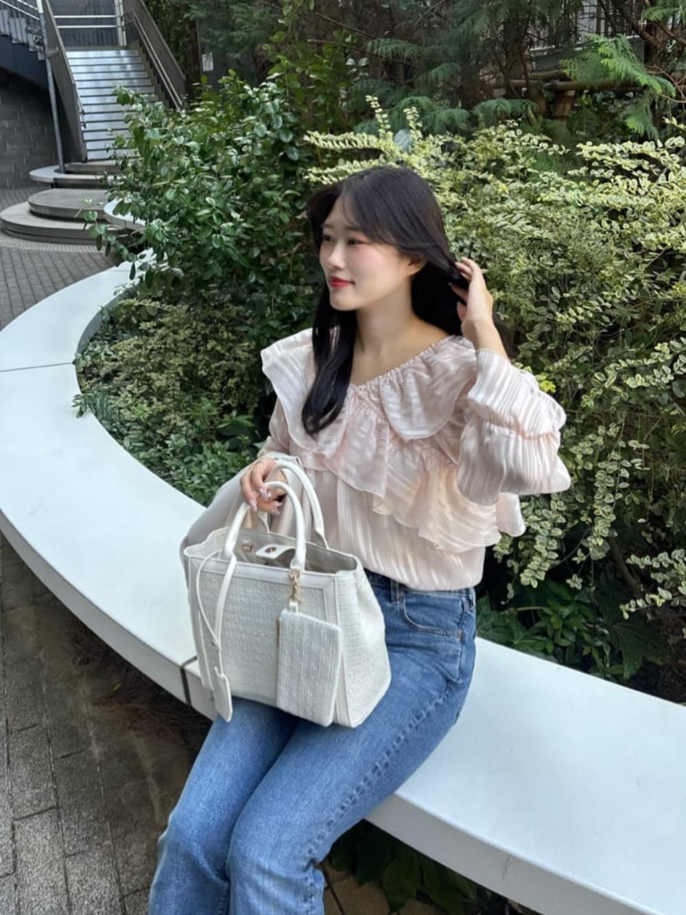 ブルー系のデニムパンツ、ホワイト系のハンドバッグ、ピンク系のシャツ/ブラウスを着用したレディースの冬コーディネートの4枚目の写真