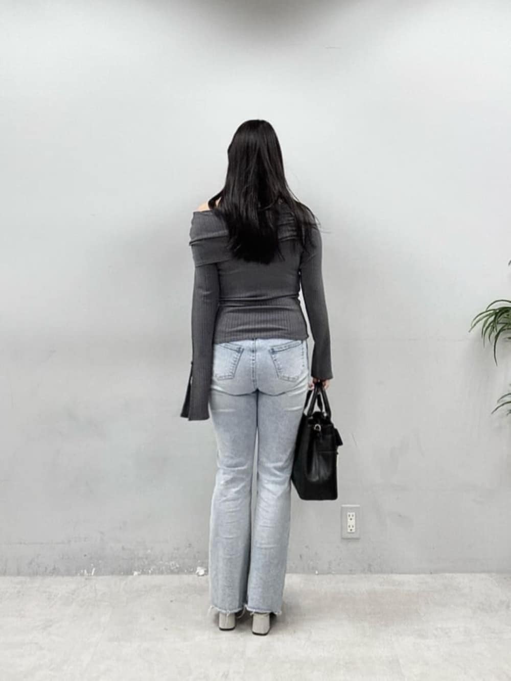 ブルー系のデニムパンツ、ブラック系のショルダーバッグ、グレー系のニット/セーターを着用したレディースの春コーディネートの3枚目の写真