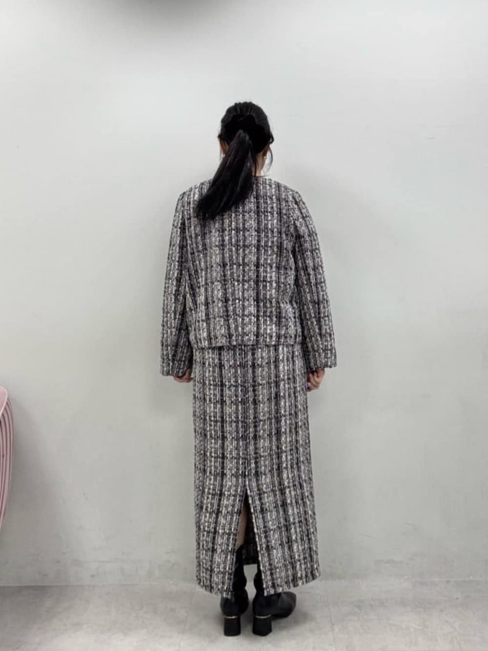 グレー系のスカート、グレー系のノーカラージャケット、ブラック系のブーツを着用したレディースの秋コーディネートの7枚目の写真