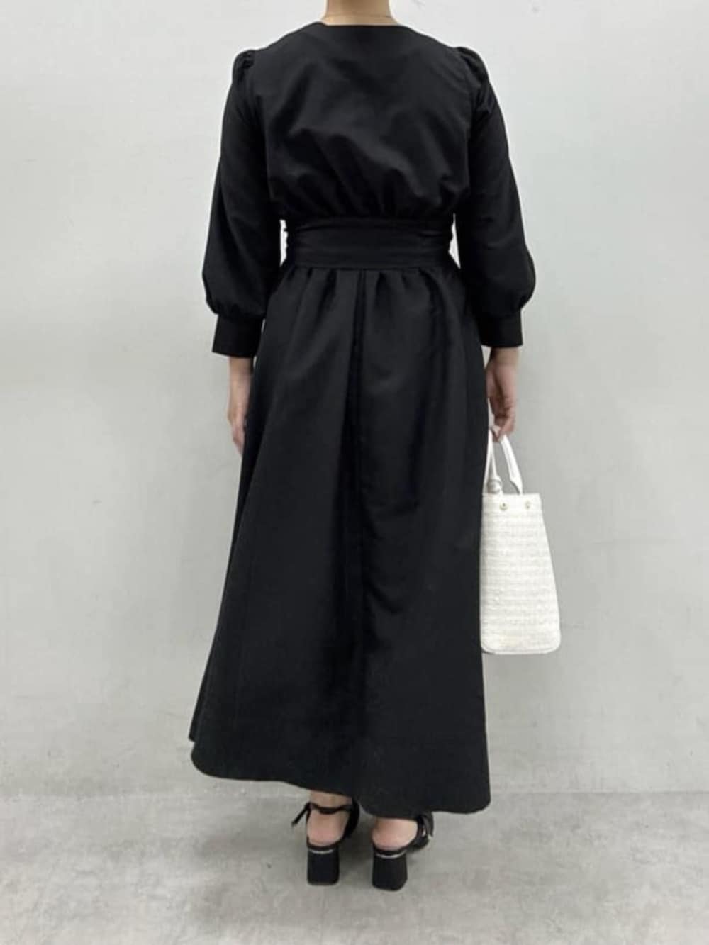 ブラック系のサンダル、ホワイト系のハンドバッグ、ブラック系のワンピースを着用したレディースの冬コーディネートの3枚目の写真