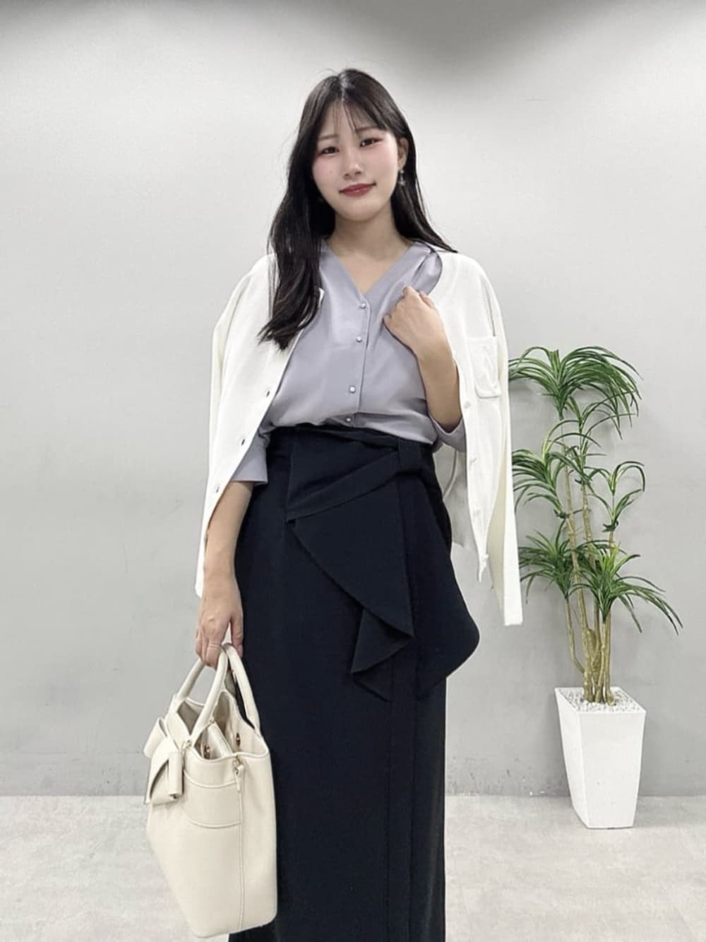 ブラック系のスカート、ホワイト系のカーディガン/ボレロ、ブルー系のシャツ/ブラウスを着用したレディースの春コーディネートの2枚目の写真